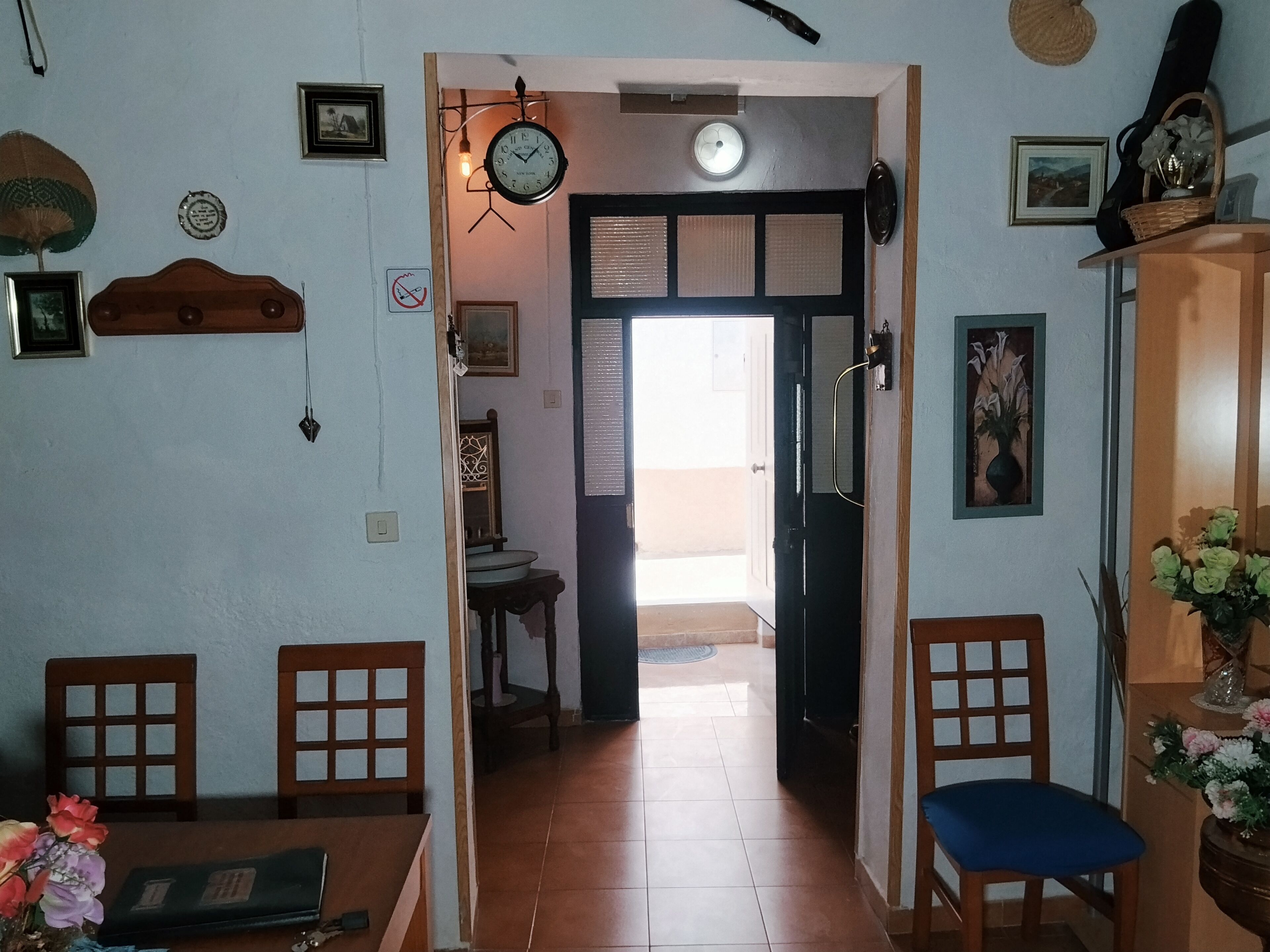 Un comedor con una mesa, sillas, un reloj y una puerta que da a otra habitación.