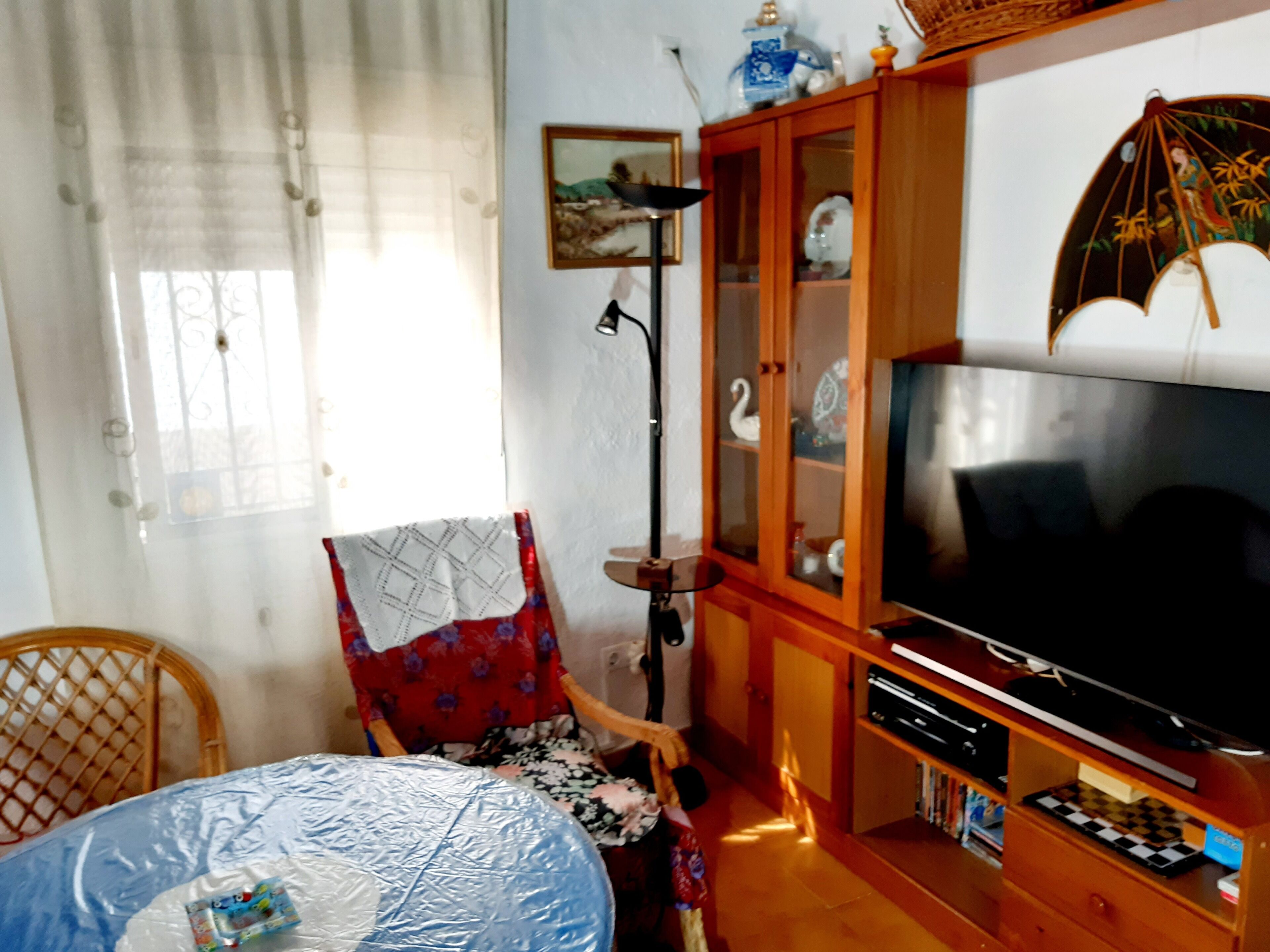 Una sala de estar con televisión, aparador de madera y un sillón.