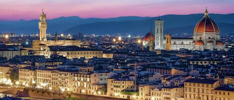 A cityscape at dusk with prominent historical architecture, including a tower and a dome.