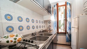 A kitchen with a gas stove, two sinks, and a refrigerator.