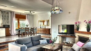 Una sala de estar con sofá, mesa de centro, televisor, chimenea y comedor.
