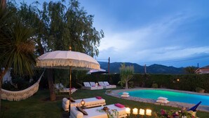A poolside area with lounge chairs, a hammock, and a table with candles.