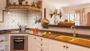 A kitchen with a stainless steel dishwasher, a double sink, and a tiled backsplash with a decorative pattern.