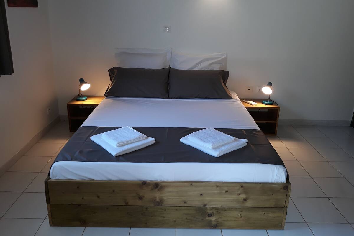 A neatly made bed with two pillows, a wooden headboard, and two bedside lamps.
