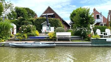 A canal with a rowboat docked, a bench, and a building with a sign.