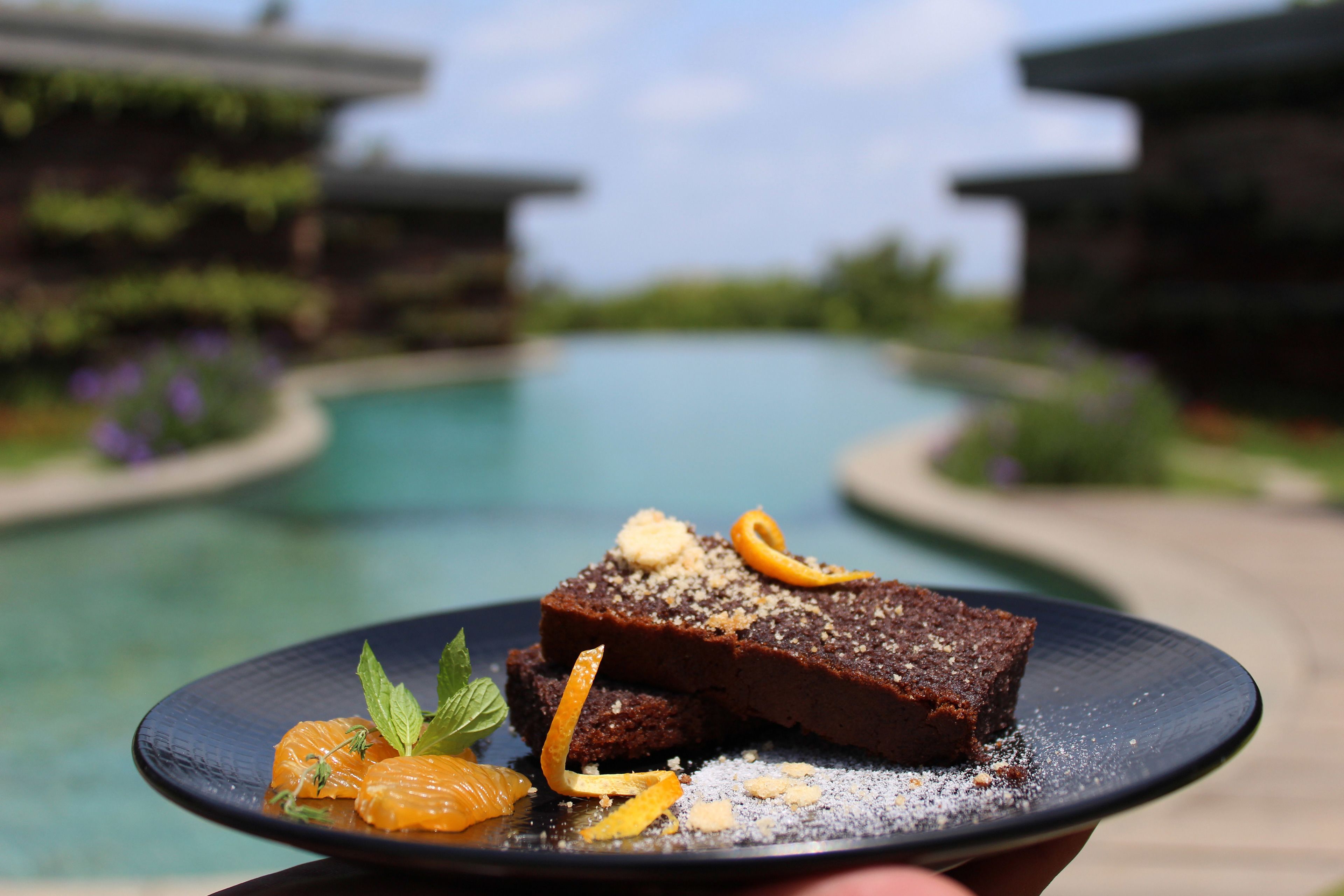 A dessert plate with a slice of cake, orange peel, and mint leaves.