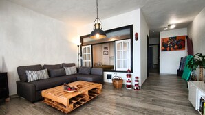 A modern living room with a dark grey sofa, a wooden coffee table, and a large mirror. - Relax in front of the Ocean with a beautiful view! (Sardina del Norte)