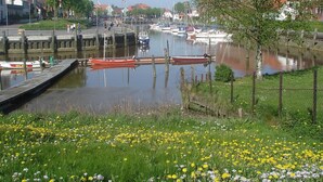 A marina with boats docked, a grassy area with flowers, and a clear sky.