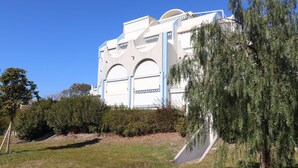 A modern building with a unique architectural design, featuring arched windows and a sloped roof. - 2 rooms cabin on the ground floor terrace (LE GRAU DU ROI)