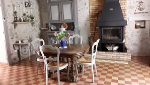 Un comedor con piso a cuadros, una mesa de madera, sillas blancas y un florero con flores.