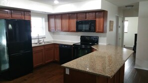 Kitchen with a window offering a view of the outside, featuring a refrigerator, dishwasher, stove, and microwave.
