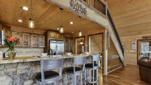 Una cucina rustica con isola in pietra, sgabelli da bar in legno e soffitto in legno.