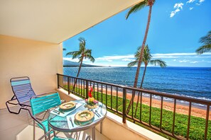 A balcony with a table set for two, overlooking a beach with palm trees and the ocean. - 🤙 Sept-Oct-Nov SPECIALS PLUS VRBO discounts 🏝️ at the LIVE ALOHA SUITE (Kihei)