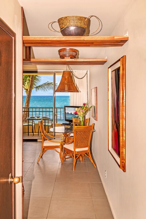 A dining area with a view of the ocean, wooden furniture, and a television. - 🤙 Sept-Oct-Nov SPECIALS PLUS VRBO discounts 🏝️ at the LIVE ALOHA SUITE (Kihei)