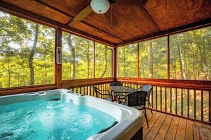 Ein Whirlpool auf einer Holzterrasse mit Blick auf einen Wald.