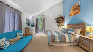 Ein Schlafzimmer mit Bett, Sofa, Fernseher, Fenster und einem Gemälde.