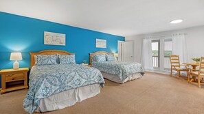 Ein Zimmer mit zwei Betten, einem Esstisch mit Stühlen und einem Balkon mit Blick.