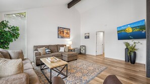 Ein Wohnzimmer mit einer Couch, einem Couchtisch und einem an der Wand befestigten Fernseher.