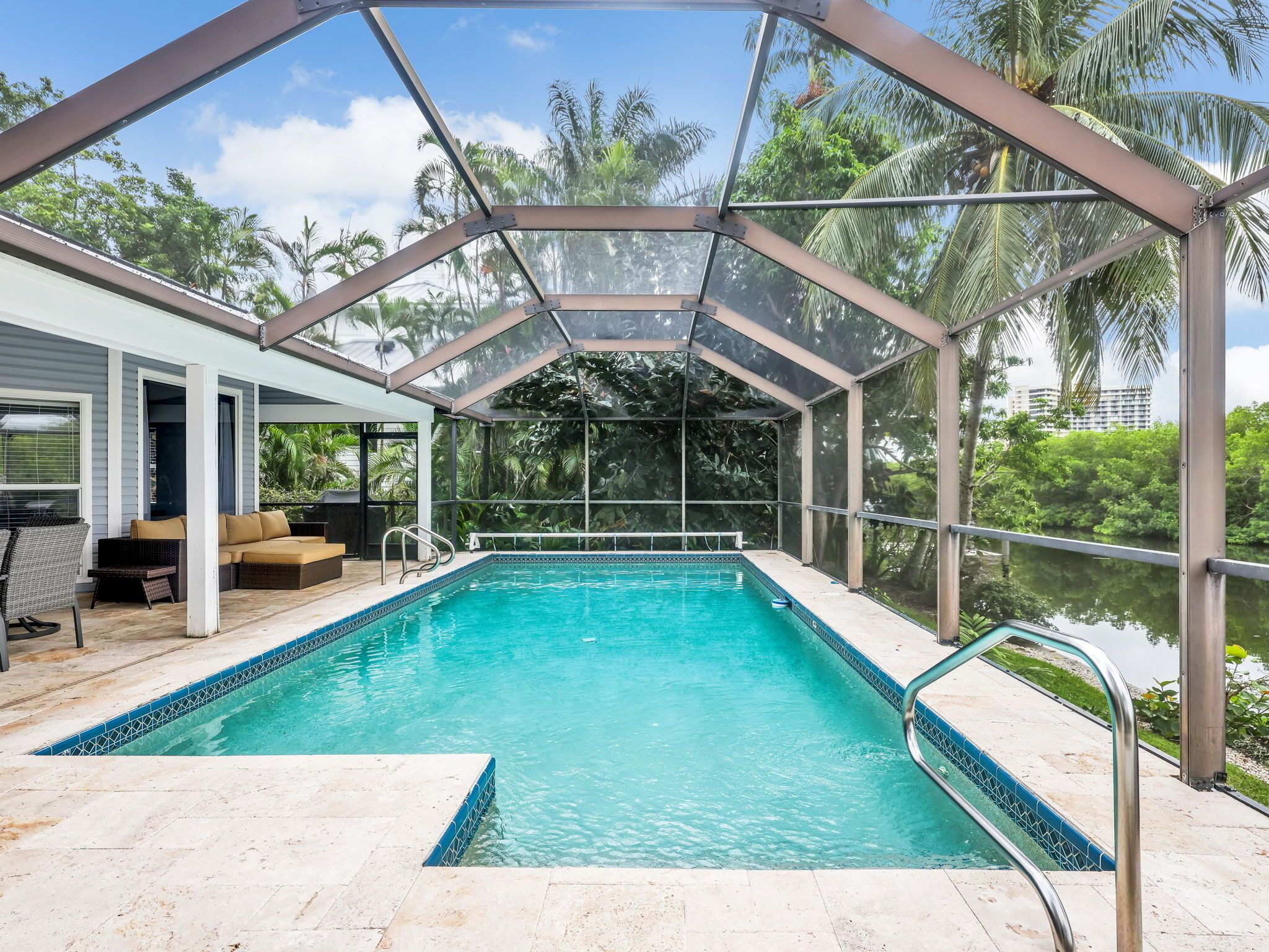 Una piscina techada con techo de vidrio, rodeada de exuberante vegetación y vistas a la ciudad.