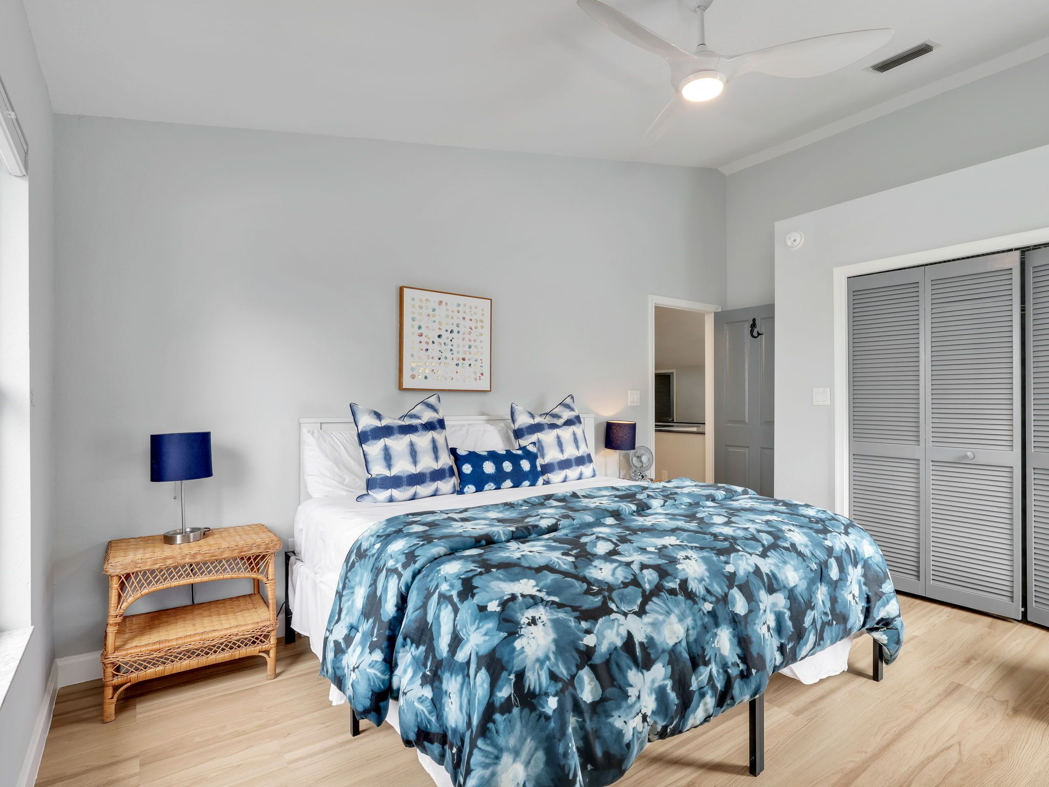 Una camera da letto con un letto, un comodino con una lampada, un'opera d'arte appesa al muro e un armadio.