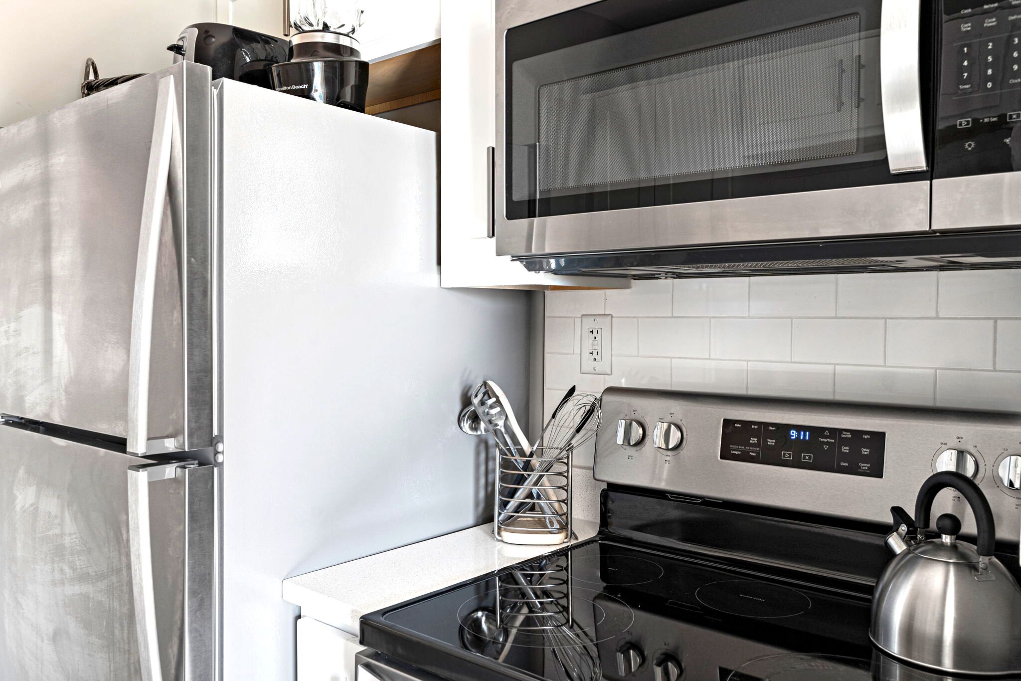 A kitchen with a stainless steel refrigerator, microwave, and stove.