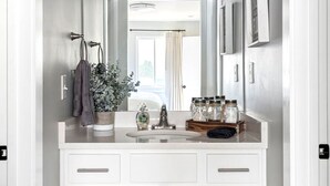 A bathroom with a white vanity, a mirror, and a light fixture above the mirror. - Bright, Cozy Riverfront Condo walkable to Downtown Nashville! (Nashville)