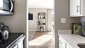 A modern kitchen with a microwave, kettle, and a countertop with books. - Bright, Cozy Riverfront Condo walkable to Downtown Nashville! (Nashville)