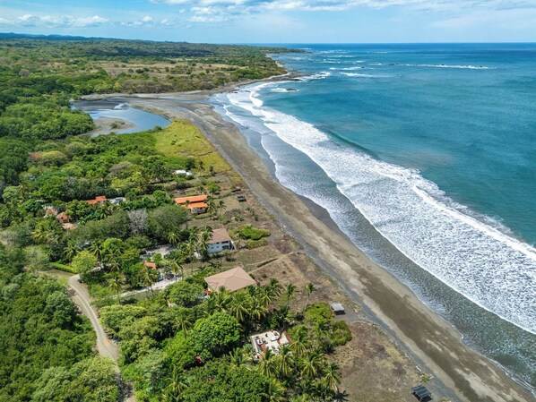 Une vue aérienne d’une zone côtière avec une plage, des maisons et une végétation luxuriante.