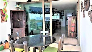 Comedor con una mesa redonda de vidrio, sillas de madera y un ventilador de techo.