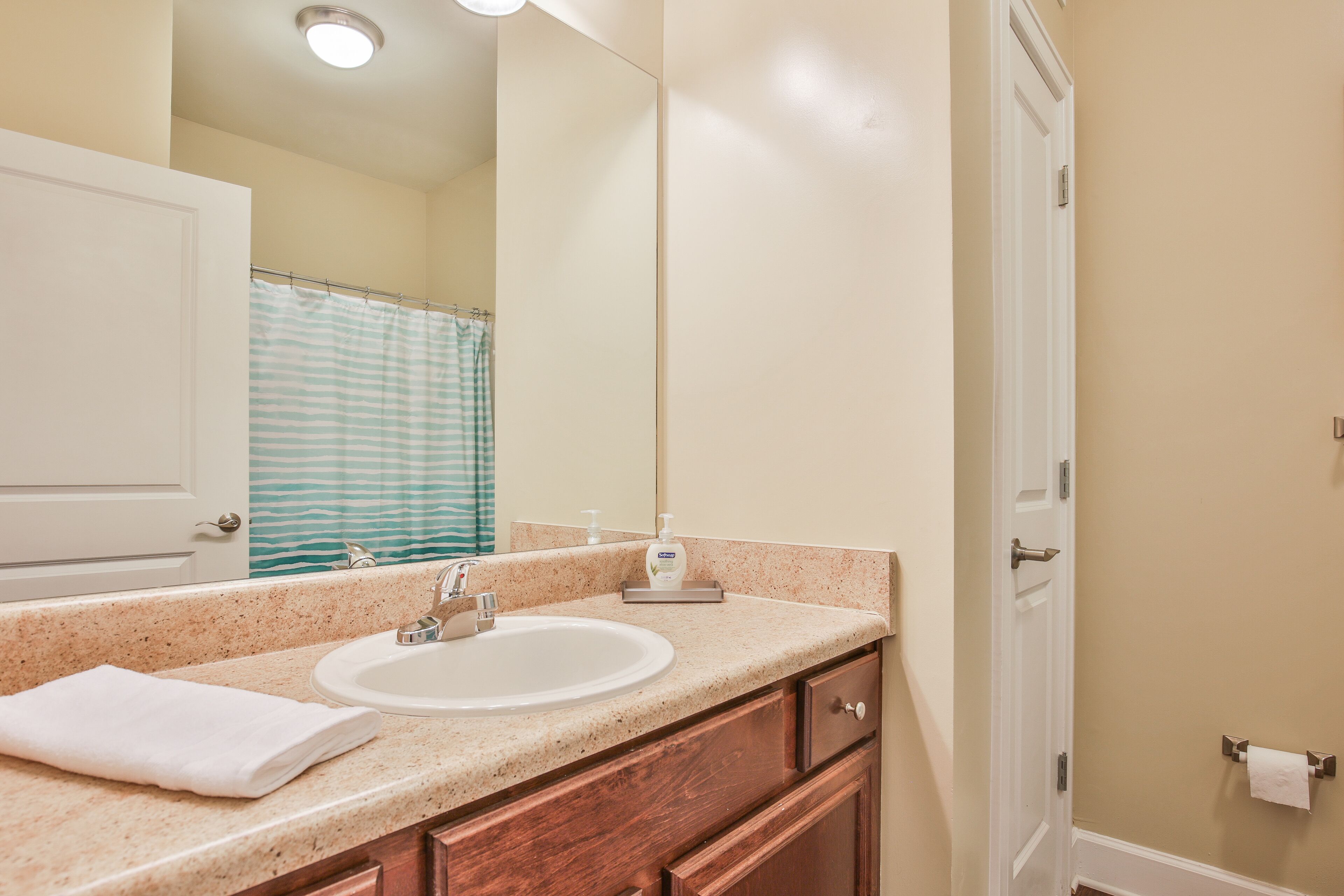 A bathroom with a sink, mirror, and a towel on the counter.