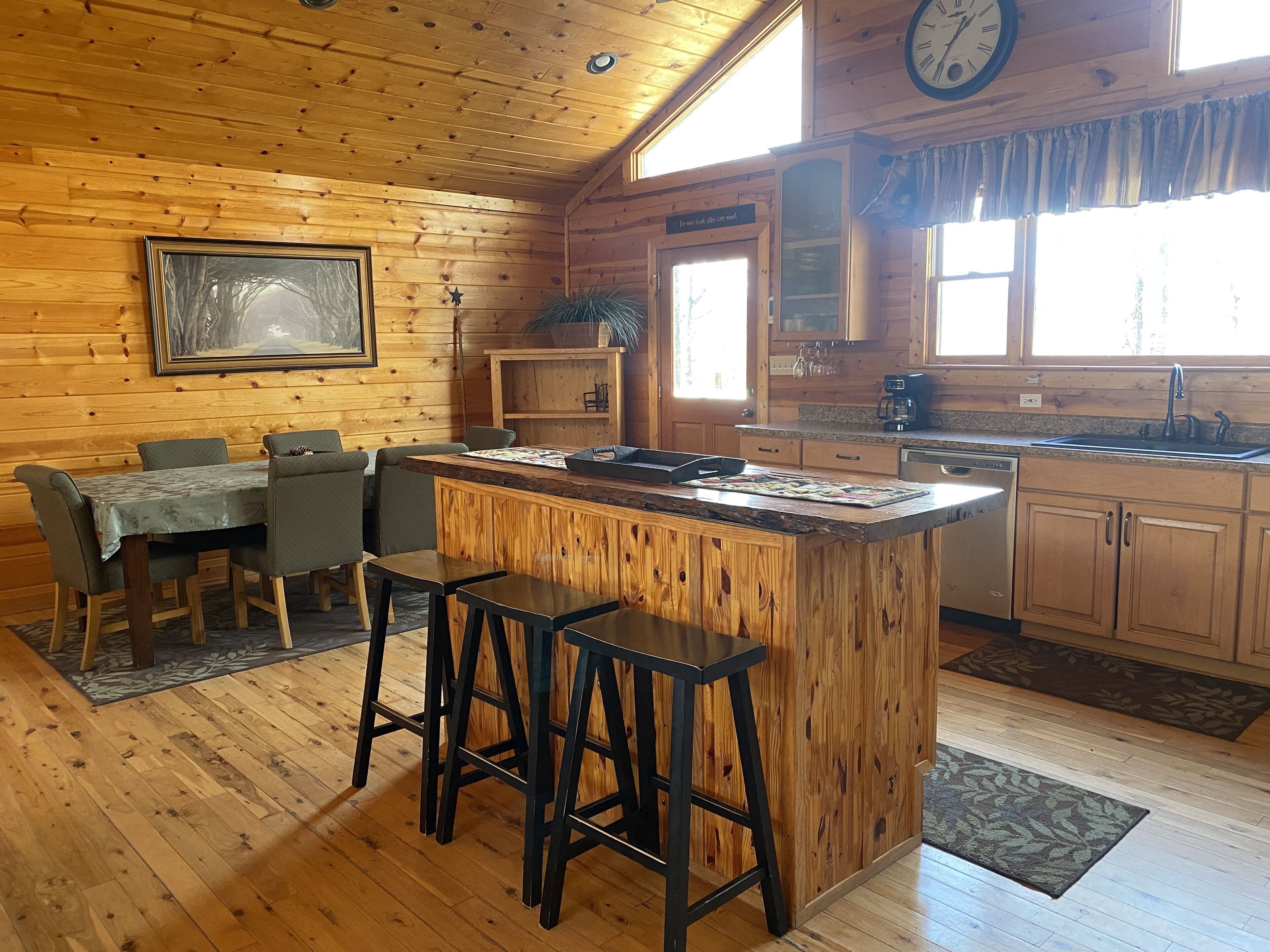 L’intérieur d’un chalet en bois comprend un coin repas, une cuisine et des tabourets de bar.