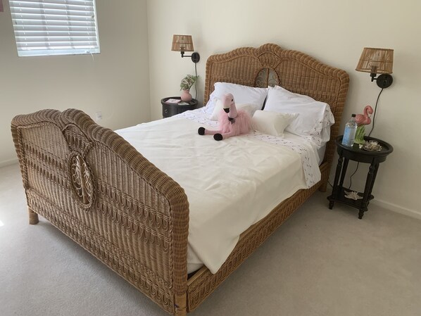 A wicker bed with white bedding, two bedside tables with lamps, and a small potted plant. - Private Beach West Bay Club, Estero, gated community (Estero)