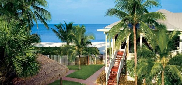 A resort with a beach view, palm trees, and a thatched-roof structure.