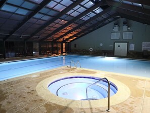 An indoor swimming pool with a hot tub, clear glass ceiling, and safety signs. - Beautiful 1 BD/1 BA Echota condo with a magnificent view of Grandfather Mtn (Boone)