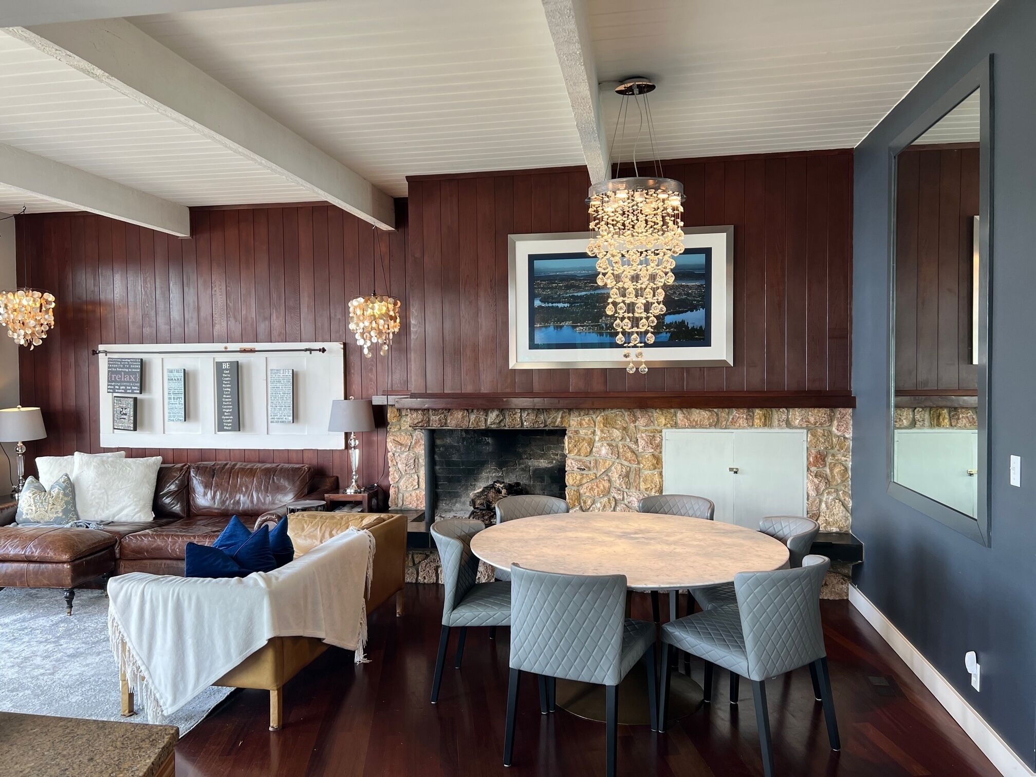 A cozy living room with a fireplace, a dining area with a round table and chairs, and a large window.