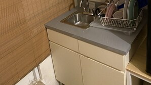 Pieni, käytännöllinen keittiö, jossa on pesuallas, kaappeja ja astiateline.