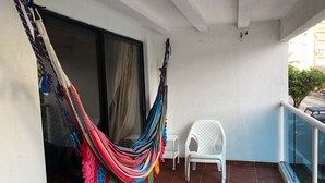 A balcony with a colorful hammock, white plastic chairs, and a glass railing. - TOP LOCATION SAN ANDRES (San Andrés)