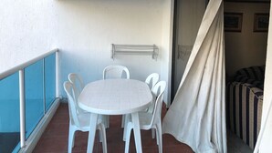 A balcony with a round table and chairs, a metal railing, and a sliding door leading to a room with striped bedding. - TOP LOCATION SAN ANDRES (San Andrés)