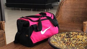 A wicker chair with a woven basket, a pink and black bag, and a black desk with a computer monitor in a room with white walls and a piano in the background. - TOP LOCATION SAN ANDRES (San Andrés)