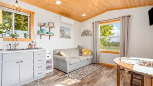 Eine gemütliche Küche mit grauem Sofa, Holzboden und einem großen Fenster mit Vorhängen.