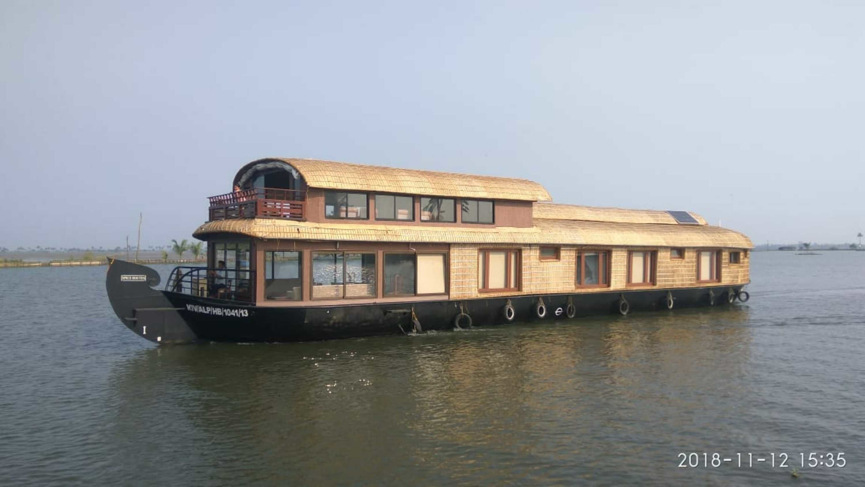Una casa flotante con techo de paja, varias ventanas y una pequeña terraza.