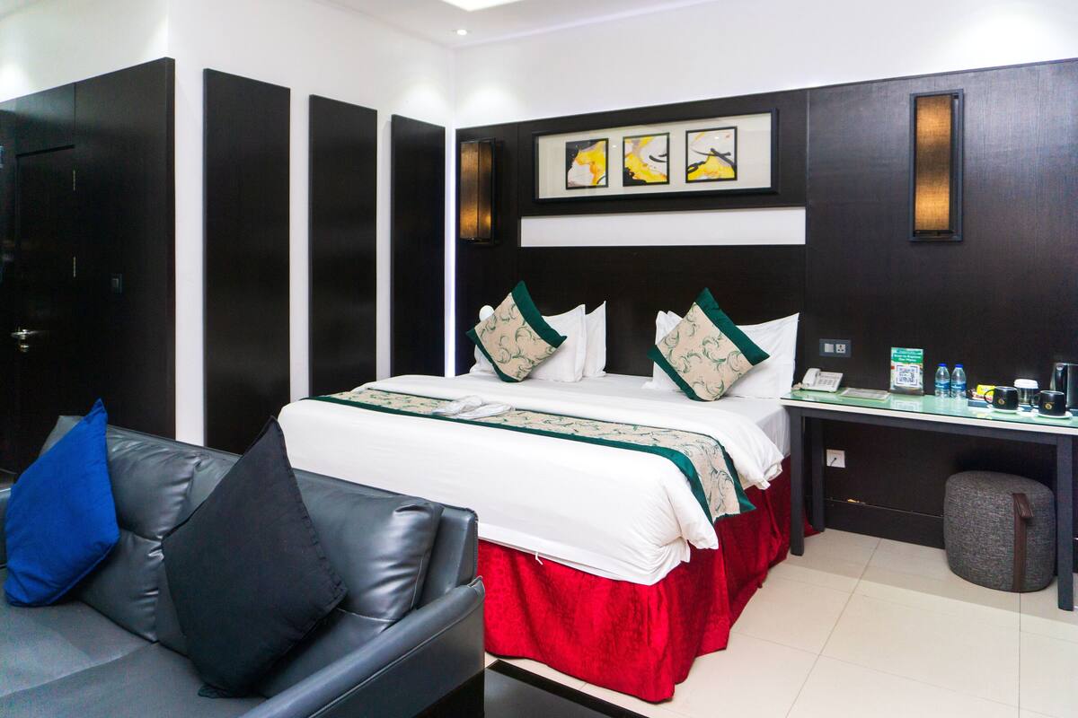 Una habitación de hotel con una cama, un escritorio, una silla y un taburete pequeño.