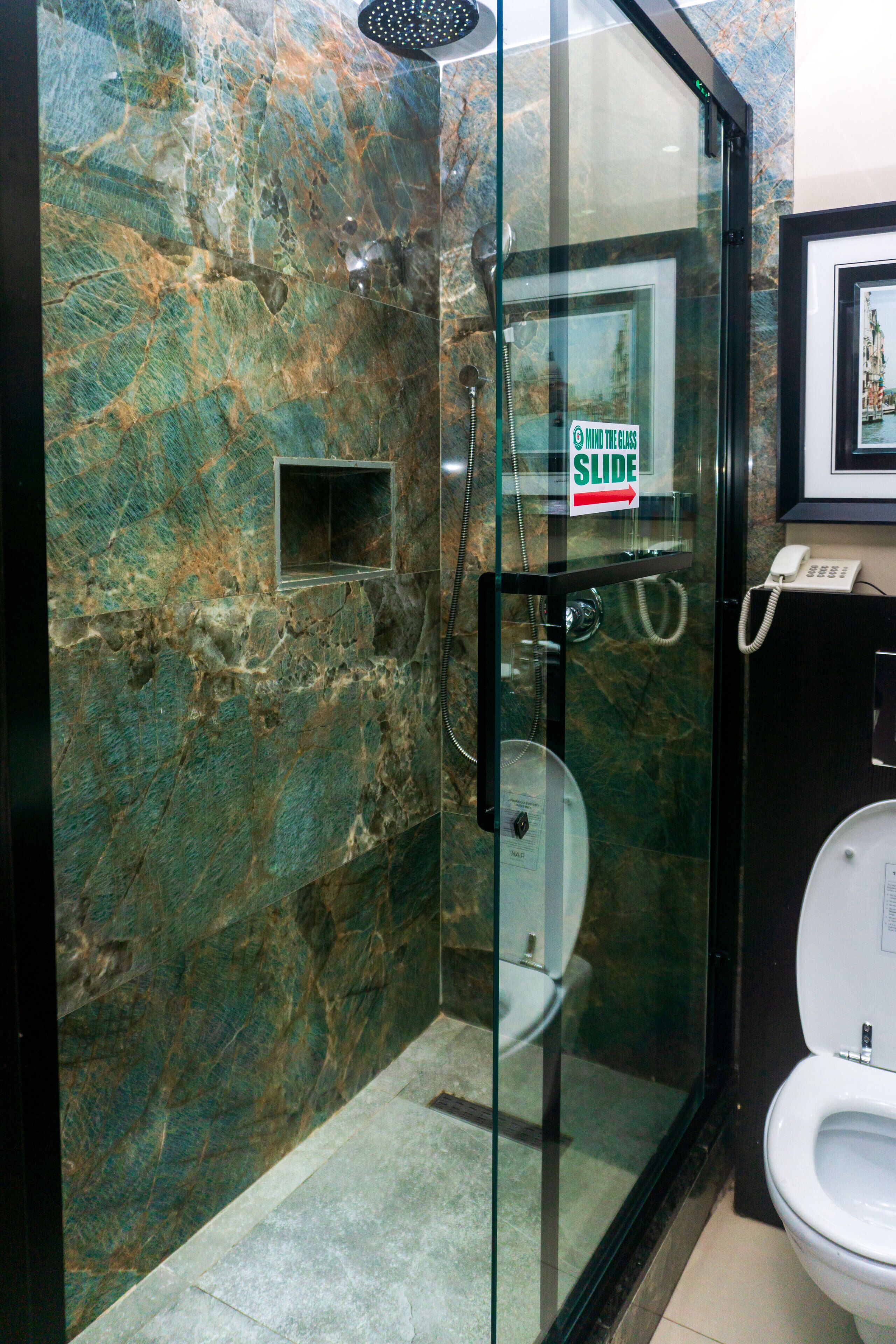 Un baño moderno con ducha acristalada, inodoro y pared de mármol.