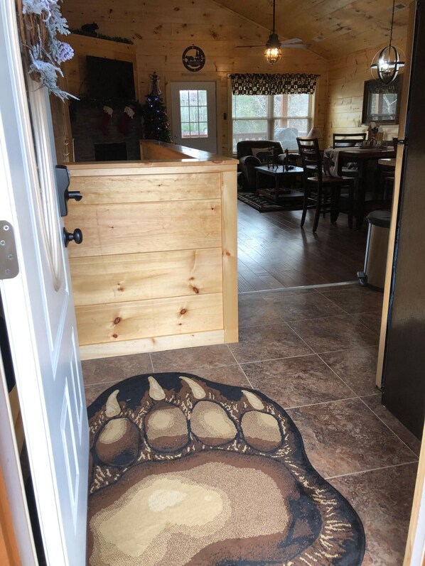 Un interior de madera con una zona de cocina, una mesa de comedor y una alfombra con motivos de hojas.