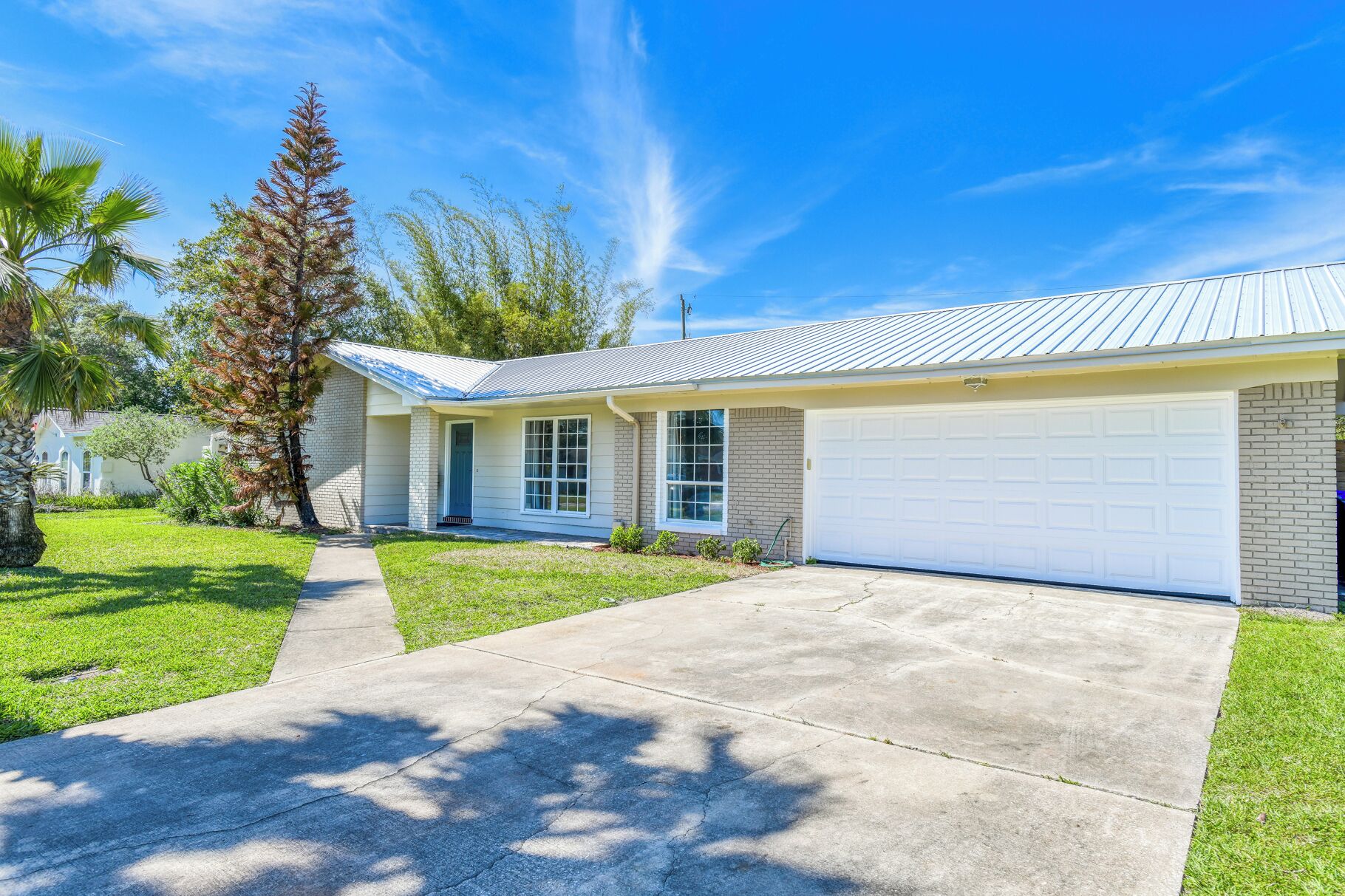 A single-story house with a garage, a front lawn, and a clear sky.