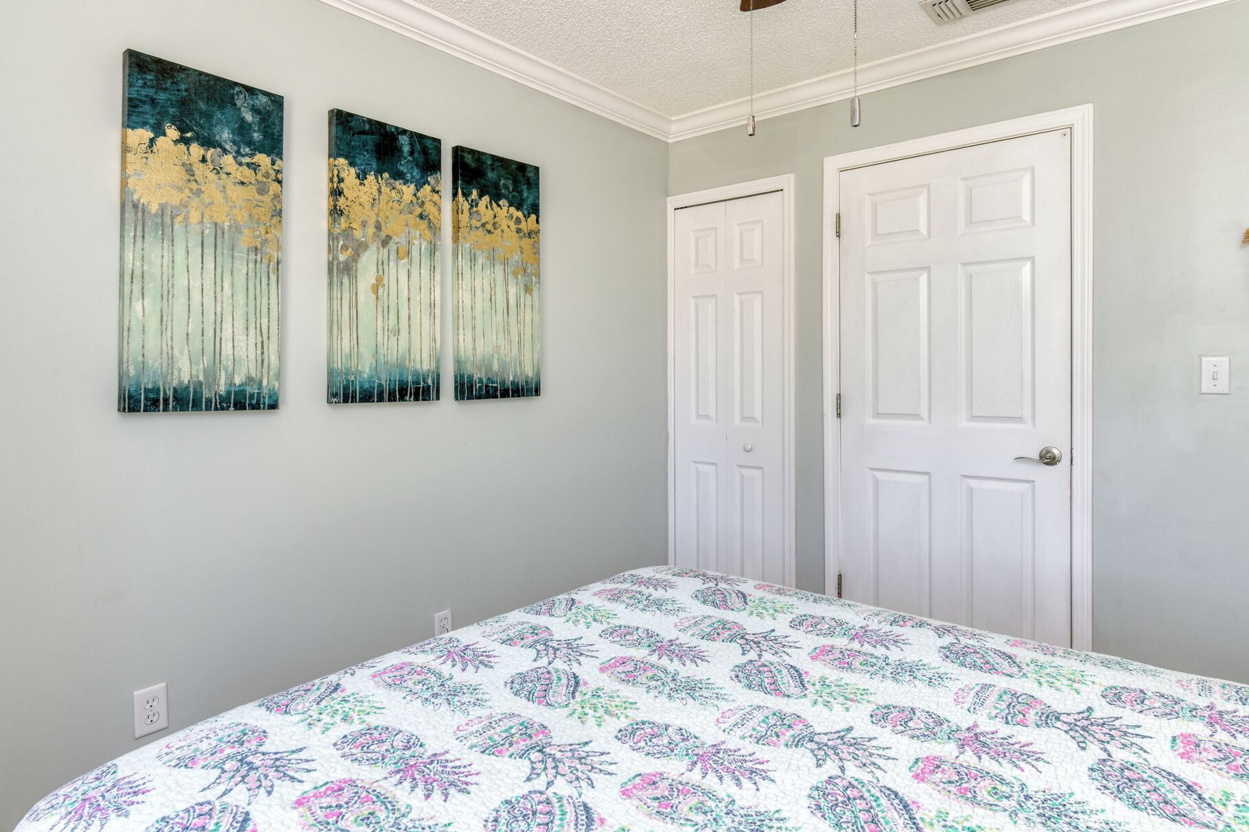 Een slaapkamer met een bed, twee deuren en drie wanddecoraties.