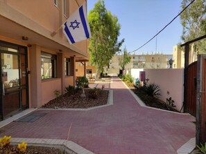 A building with a flag, a paved walkway, and a tree.
