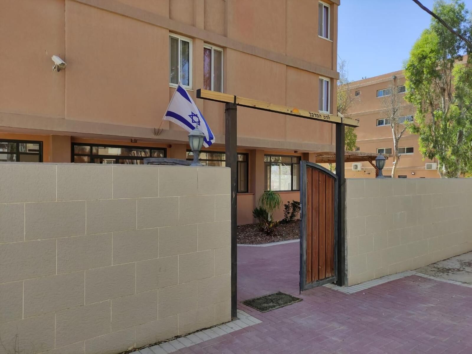 A building entrance with a flag, a gated entrance, and a paved walkway.