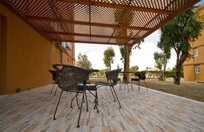 An outdoor patio with wicker furniture and a wooden pergola.