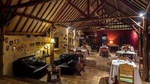 A rustic dining area with wooden beams, stone walls, and leather furniture. - Dolcemare Resort (Gili Air)